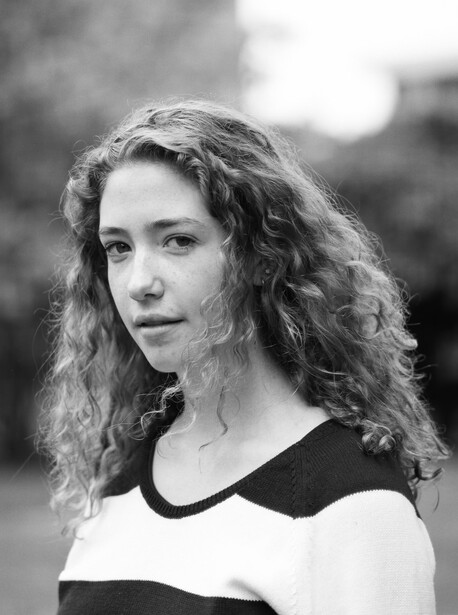 Woman with long wavy hair looking off-camera in black and white portrait photography.