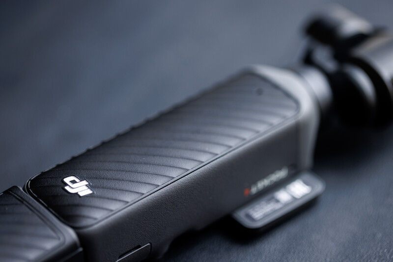 Close-up of a camera hotshoe with a wireless trigger mounted and connected cable against a gray surface.