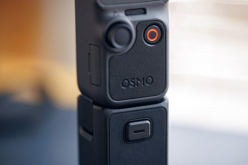 DJI Osmo Action camera mounted on extension pole with record button visible.