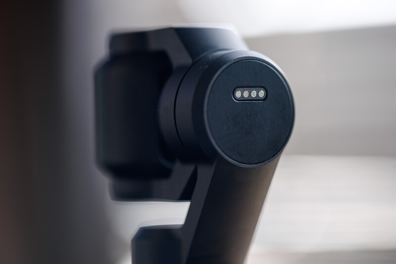 Close-up of a black gimbal stabilizer head with control dial and indicator lights.