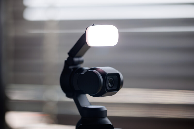 Smartphone mounted on gimbal with LED light panel attached overhead in studio setting.