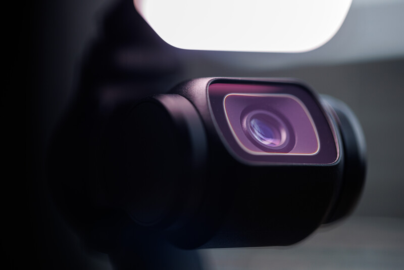 Close-up of a smartphone camera lens with pink and purple neon lighting and soft bokeh background.