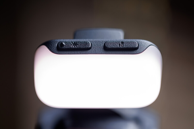 Top view of a camera flash diffuser with white translucent panel and dark control buttons.