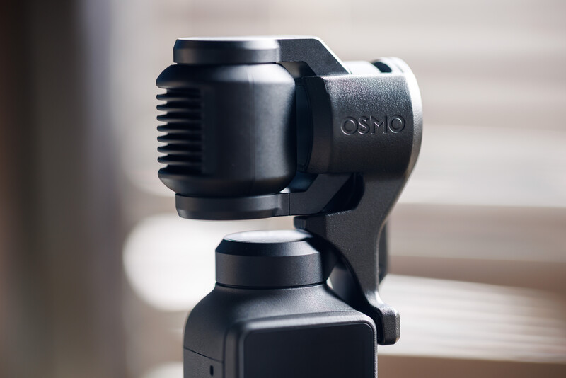 DJI Osmo gimbal stabilizer mounted on a stand, shown in profile against a soft, blurred background.
