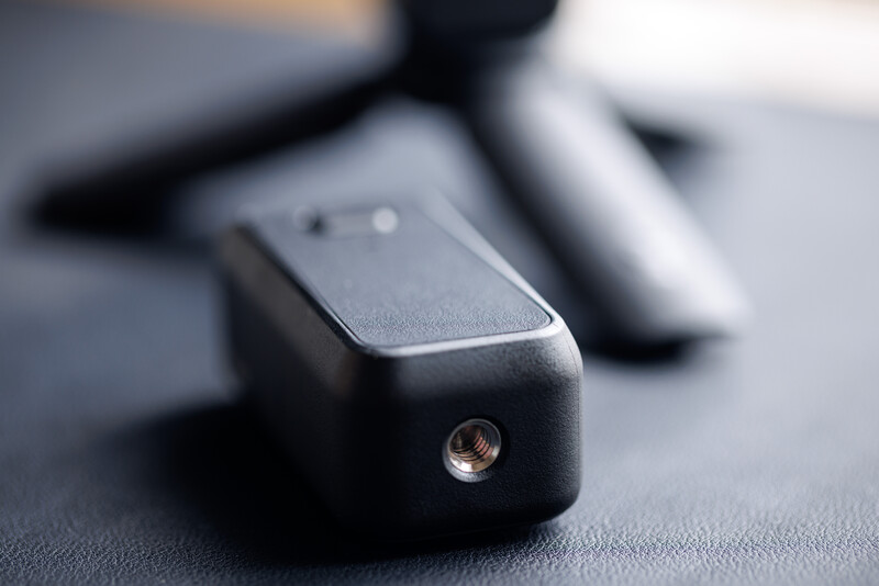 Close-up of a black audio connector with a threaded metal port on a dark fabric surface.