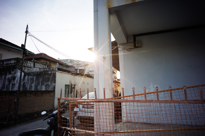 Industrial urban construction site with temporary metal fencing and modern building structure against bright sky.