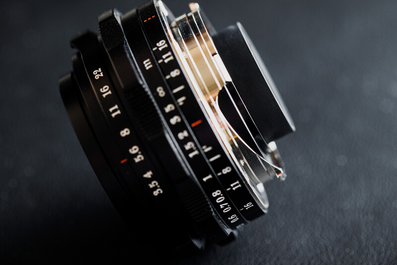 Stack of vintage camera lenses arranged at an angle, showing aperture markings and focus rings.