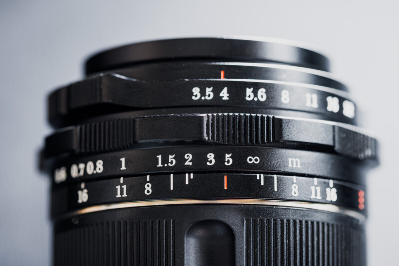 Close-up of vintage camera lens showing aperture scale, focus ring, and depth of field markings.