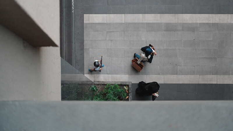 Aerial view of four people on a concrete plaza with geometric paving patterns and green planter boxes.
