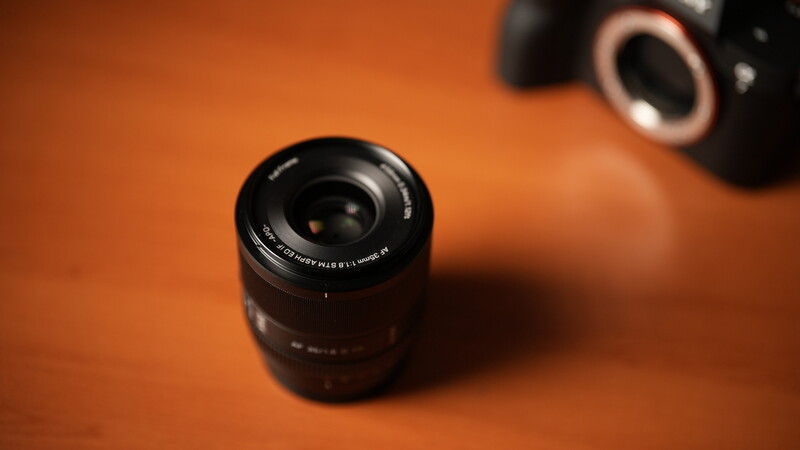 Camera lens with black barrel on warm orange studio background.