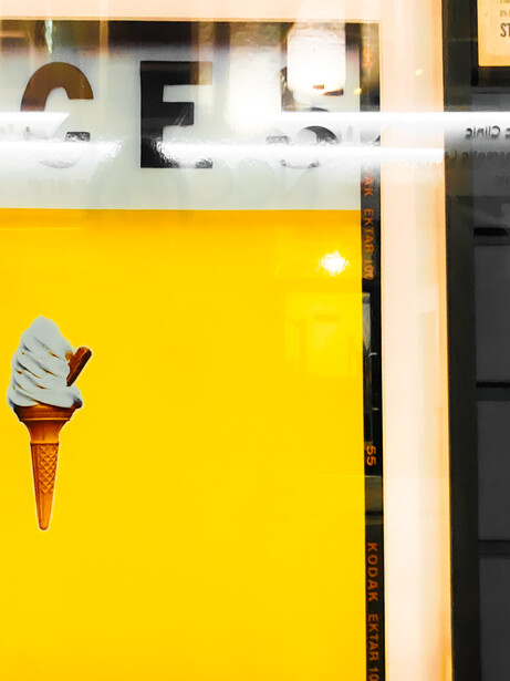 Melting ice cream cone mounted on bright yellow wall display surface.