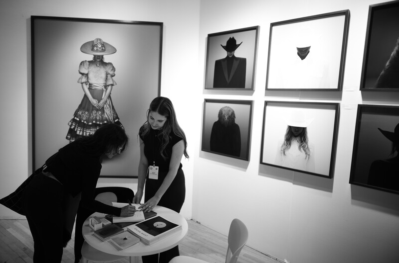 Gallery visitor viewing black and white portrait photographs displayed on white walls.