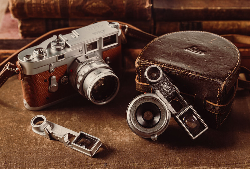 Vintage rangefinder cameras with leather cases and accessories arranged on a textured surface.