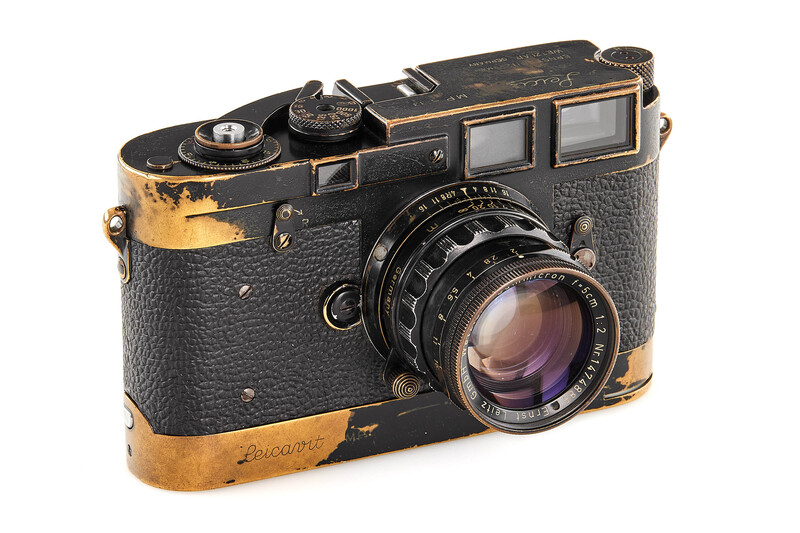 Vintage rangefinder camera with worn brass and black body, showing dual viewfinders and standard lens.