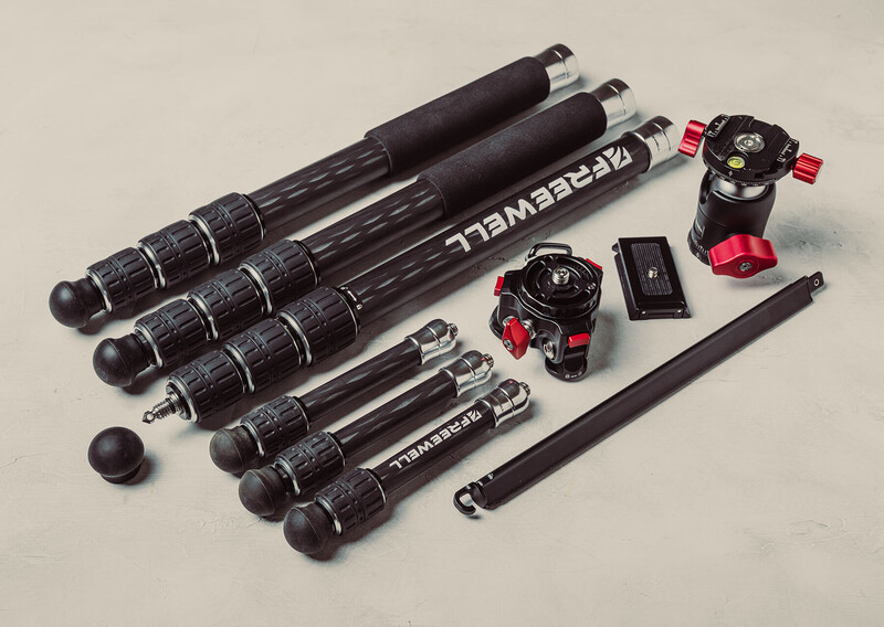 Professional tripod system with carbon fiber legs, fluid head, and accessories laid out.