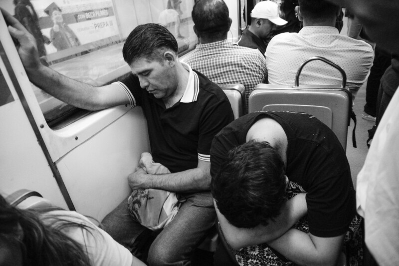 Black and white photograph of people in close quarters on what appears to be public transportation.