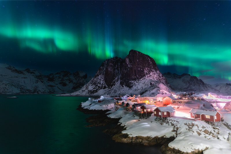 Northern lights over red cabin village in Lofoten 