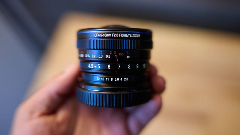 Close-up of a blue fisheye lens with depth-of-field and focus distance scales visible on the barrel.