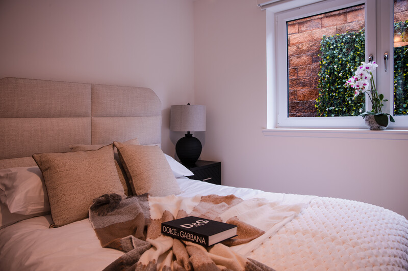 Soft-lit bedroom with blush pink walls, layered bedding, and a styled flat lay arrangement on the bed.