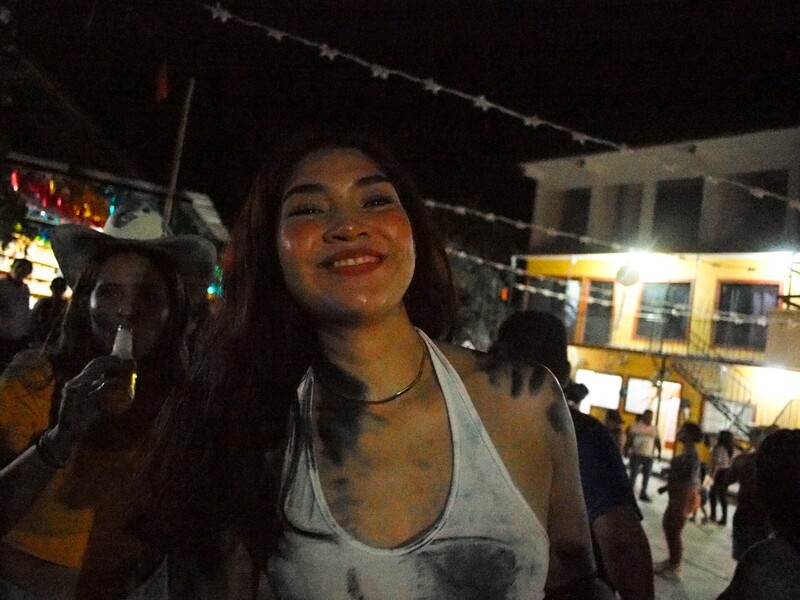 Woman smiling at night event with string lights and illuminated building in background