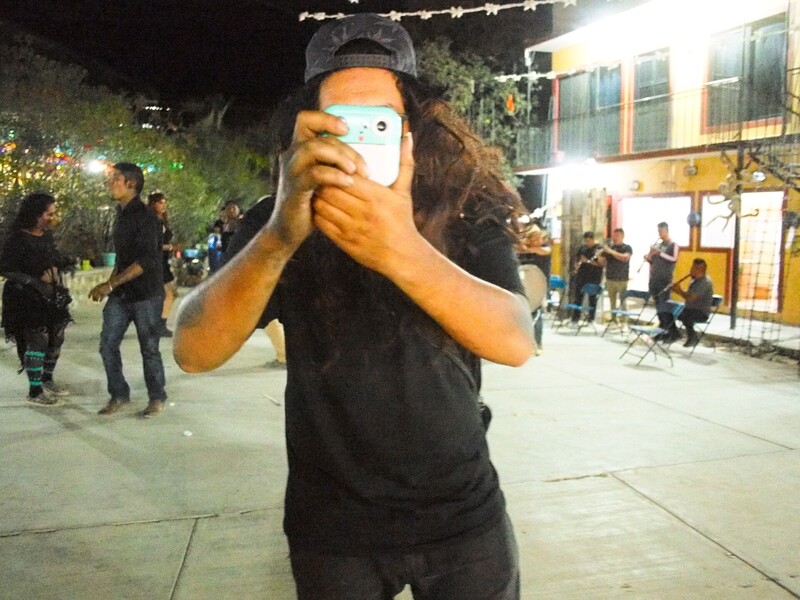 Person holding smartphone up to face at night, capturing content in outdoor urban setting
