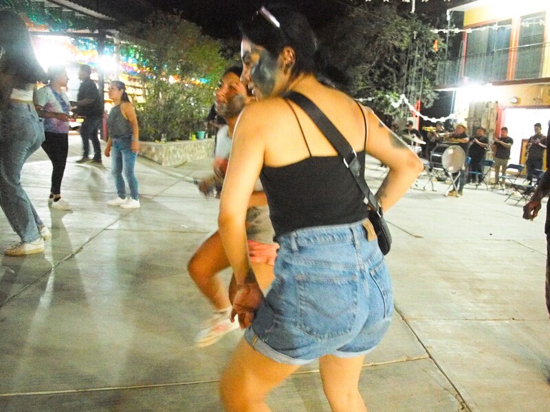 Woman in black halter top and denim shorts dancing at outdoor nighttime event