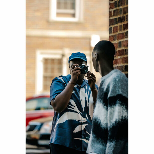 Street photographer with camera and blue cap photographing a subject outdoors