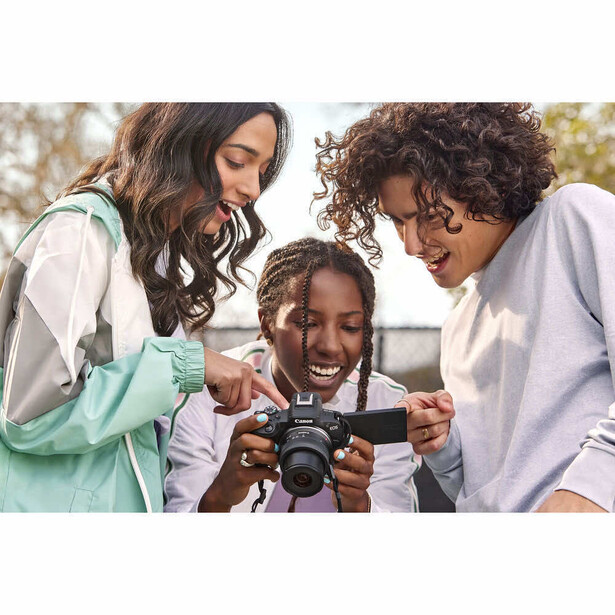 Three women reviewing photos on a digital camera outdoors