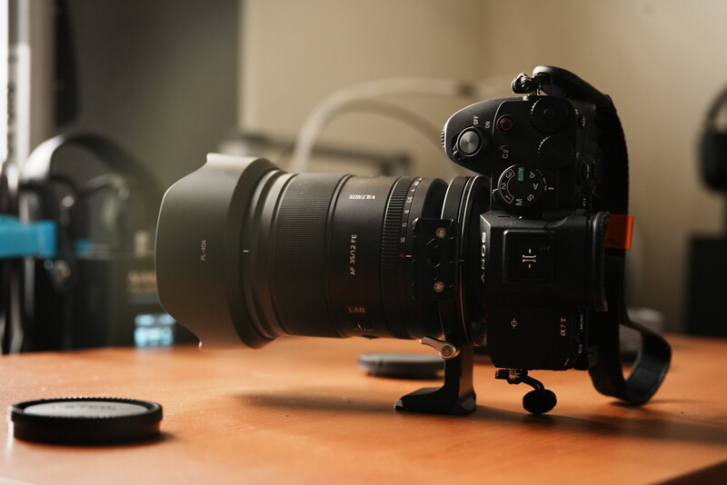 Mirrorless camera with telephoto lens mounted on wooden desk in studio setting