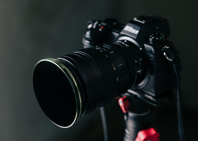 Nikon DSLR camera with wide-angle lens mounted on tripod against dark background