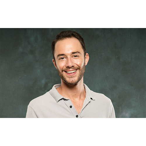 Man with dark hair and beard smiling at camera in studio portrait