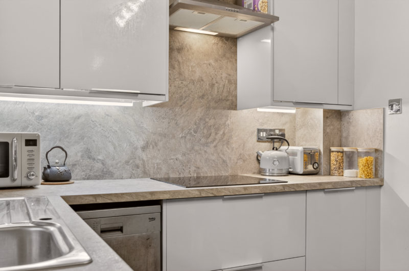 Modern kitchen with white cabinetry, marble backsplash, and stainless steel appliances