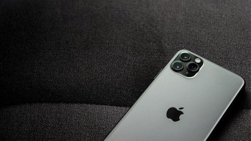 Silver iPhone 11 Pro with quad rear camera system on dark fabric surface