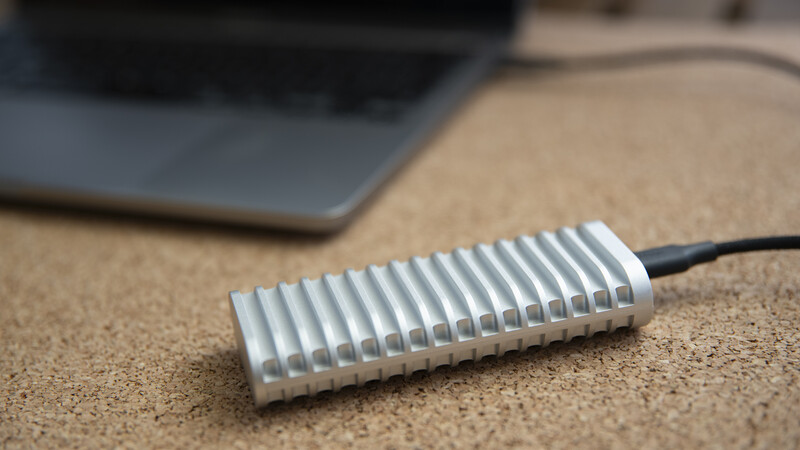 Aluminum ribbed heat sink with attached black cable on cork desktop surface