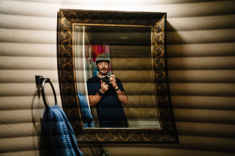 Self-portrait reflection in ornate mirror showing photographer holding camera and light modifier