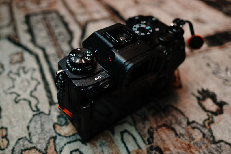 Black mirrorless camera with dual control dials on ornate patterned fabric