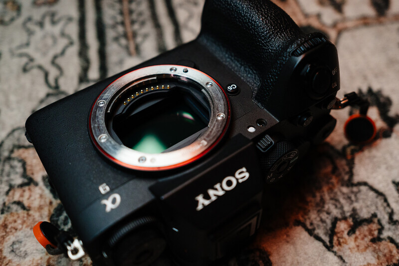 Sony mirrorless camera with lens mount exposed, displayed on a patterned textile surface