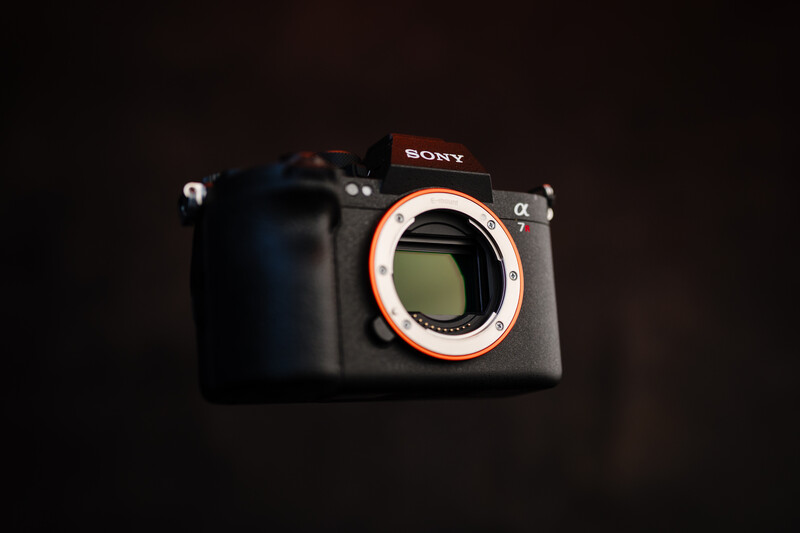 Sony mirrorless camera body with orange lens mount ring against dark background