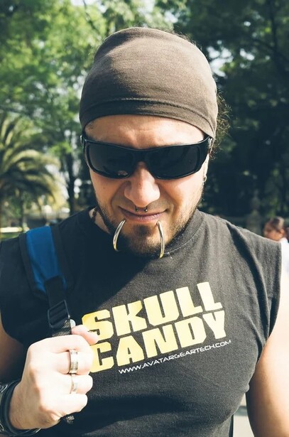 Man wearing sunglasses and beanie pointing at camera, dressed in graphic t-shirt