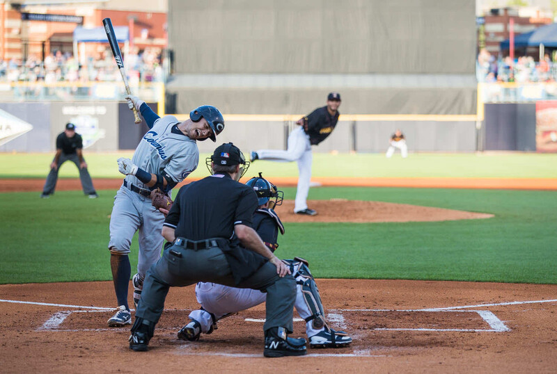Baseball batter at plate during game with catcher and umpire in foreground