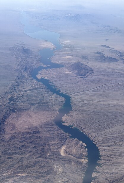 Aerial view of a winding river through agricultural landscape with cloud cover