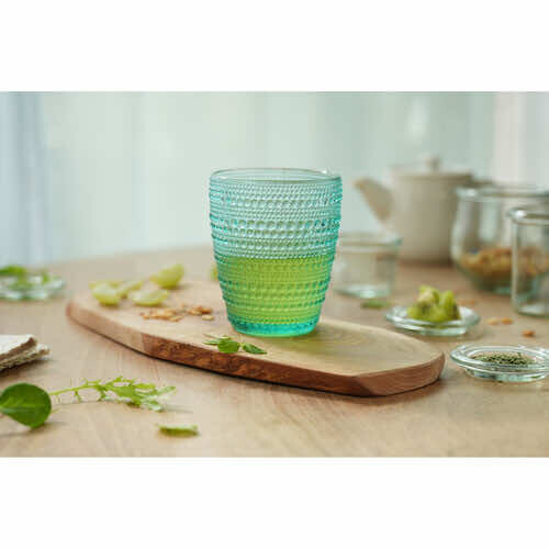 Ombré green glass on wooden platter with fresh herbs and kitchen elements