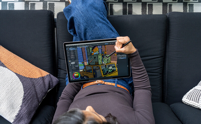 Photographer using stylus on iPad displaying colorful digital artwork with architectural floor plan overlay