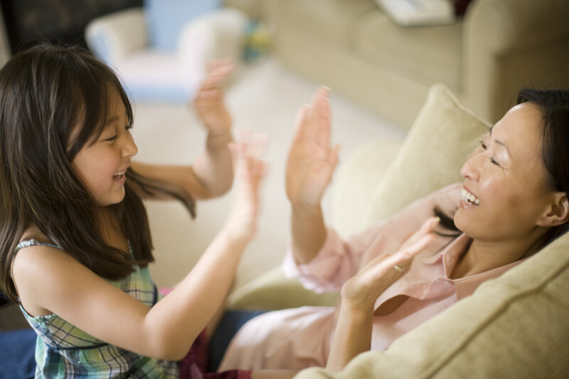 Two women laughing together on a couch during an indoor portrait session
