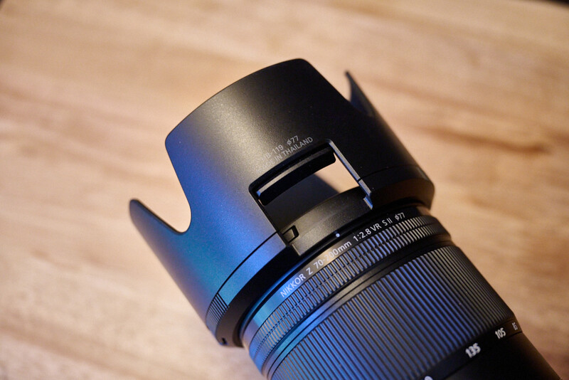Wide-angle lens with lens hood attached, displayed on wooden surface