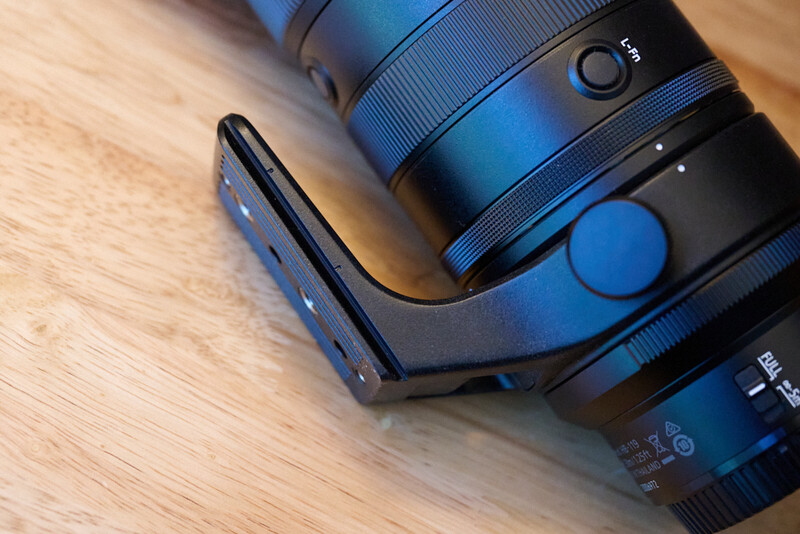Blue and black camera lens with hood and blue lens cap on wooden surface