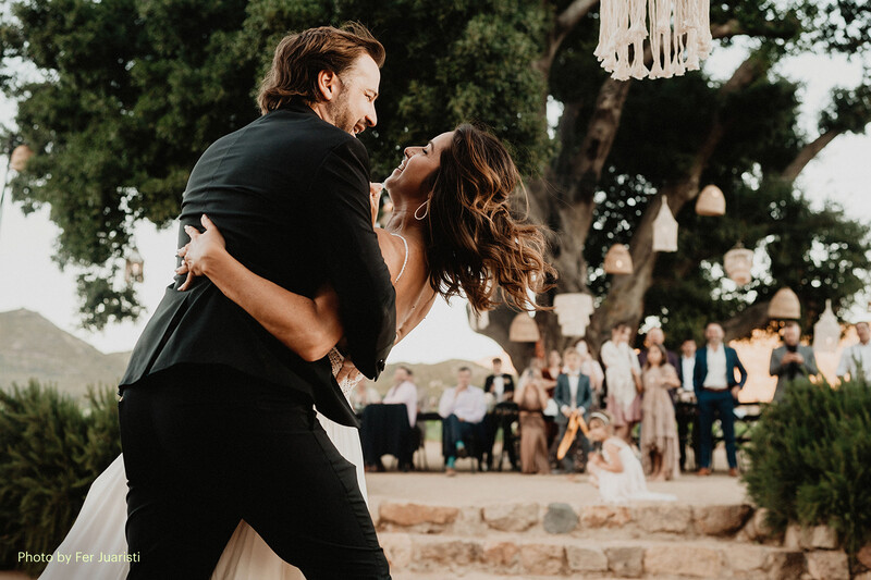 Groom lifting bride during first dance at outdoor wedding reception under tree