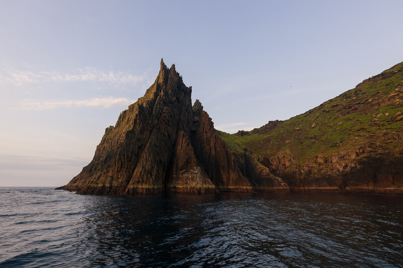 Dramatic rocky sea stack with columnar basalt formations rising from calm ocean waters
