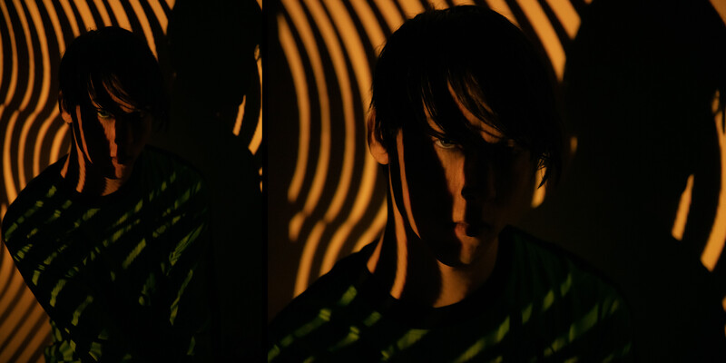 Silhouetted figures backlit by warm orange striped light pattern with green foreground elements