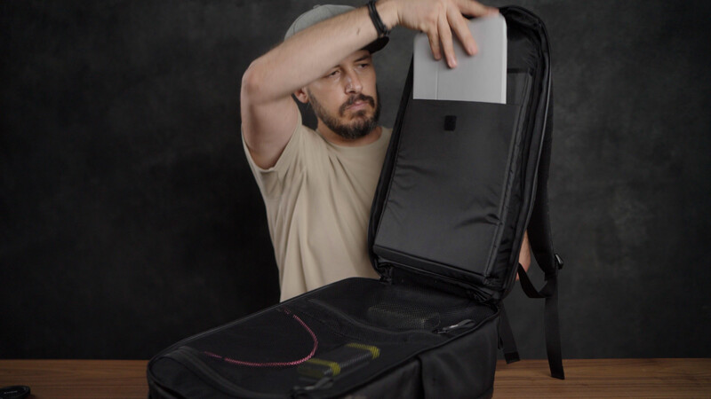 Man examining the interior of a black camera backpack with organized compartments